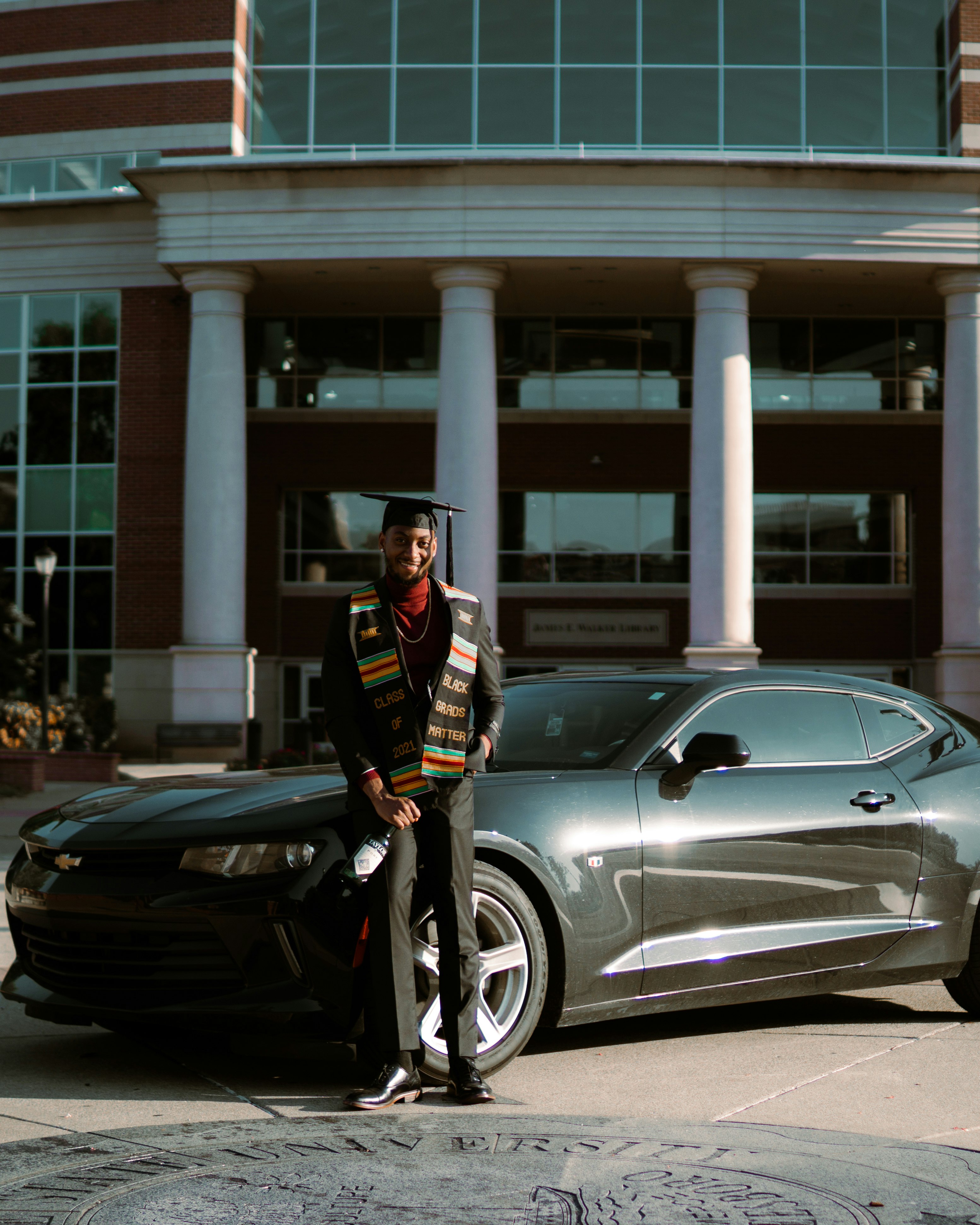 man in black and white jacket standing beside black car